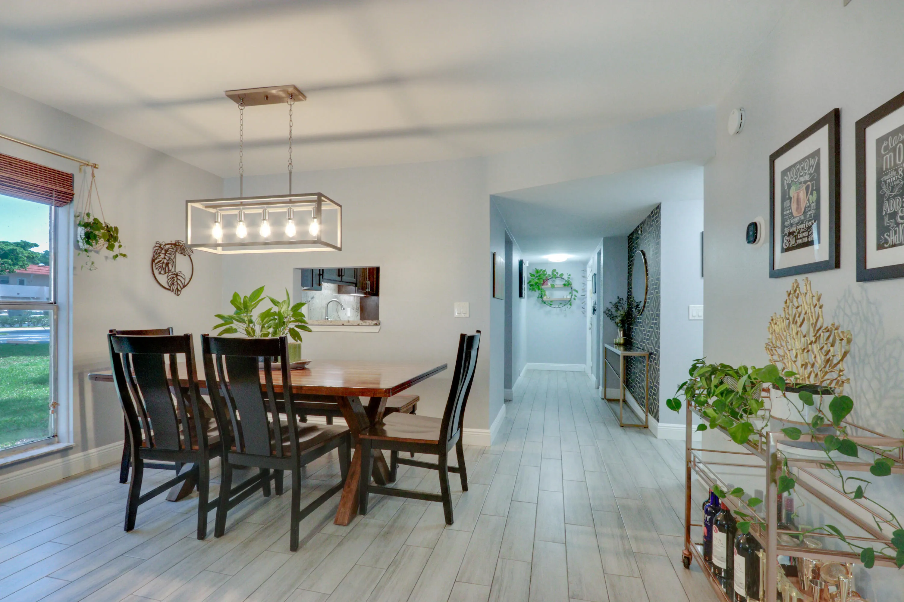 Recessed lighting, wood-finish flooring, and a contemporary chandelier illuminate this dining area