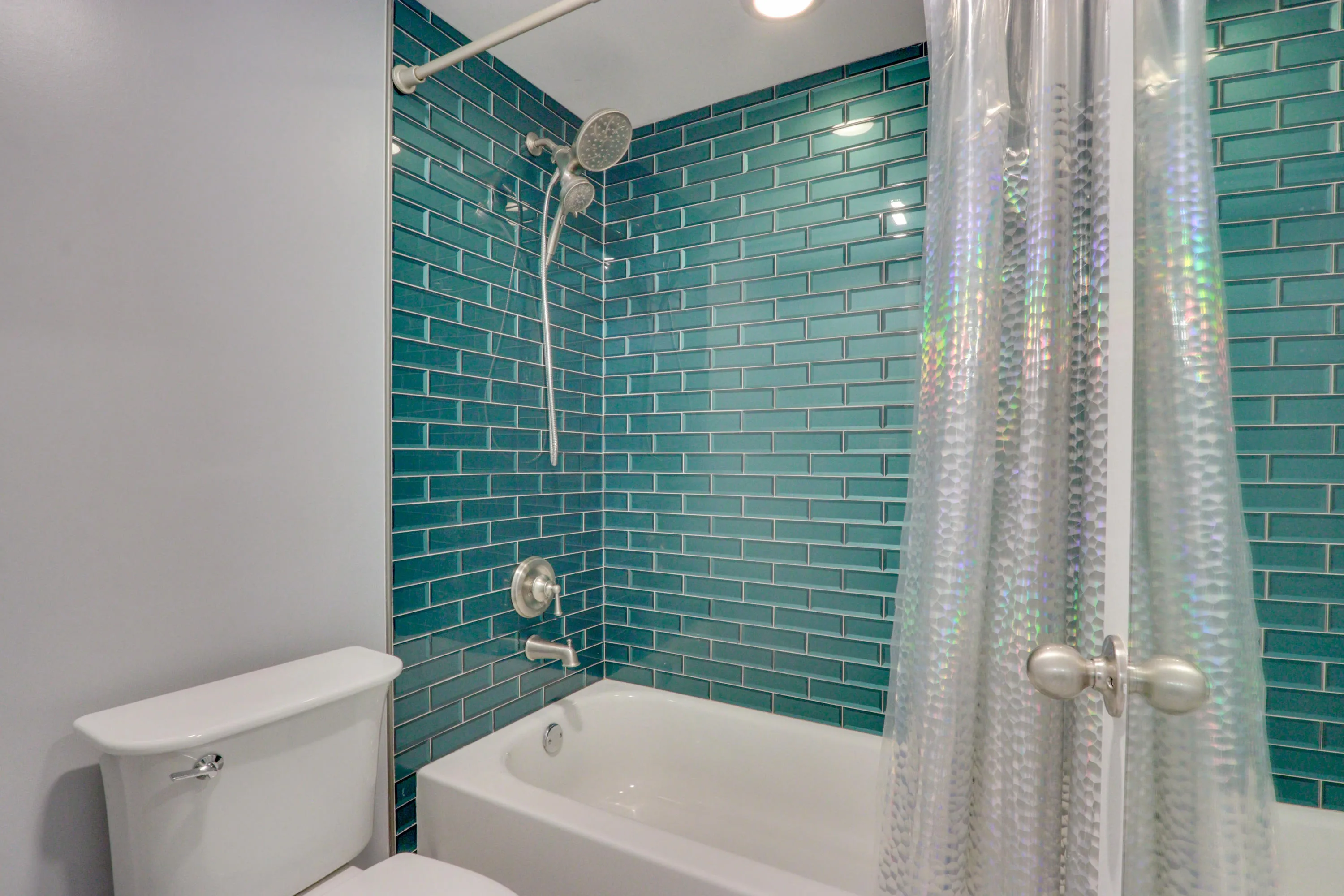Bathtub with teal subway tile surround and brushed nickel fixtures