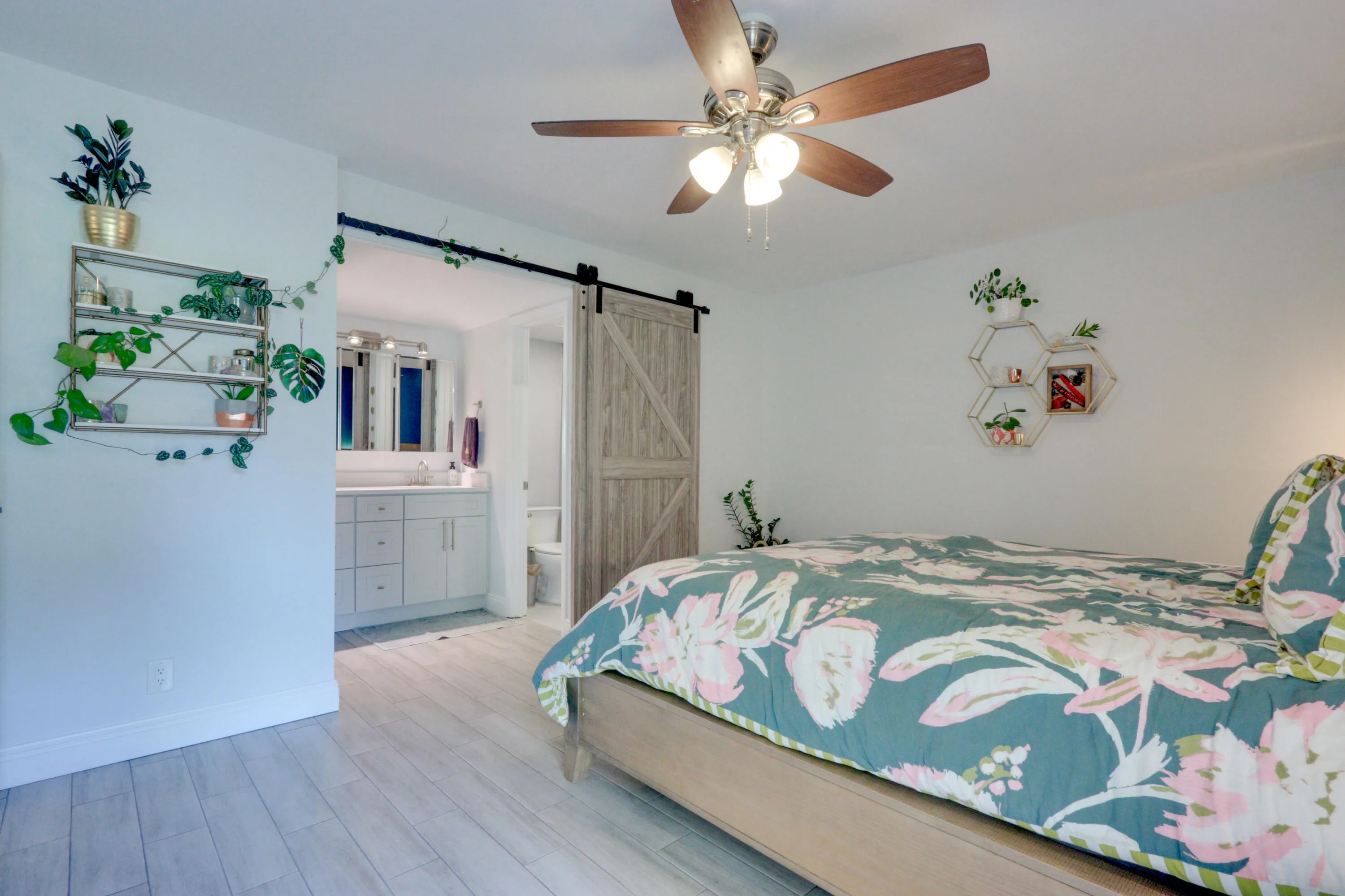 Wood-finish flooring throughout, ceiling fan with integrated lighting, and a barn door entry to the bathroom