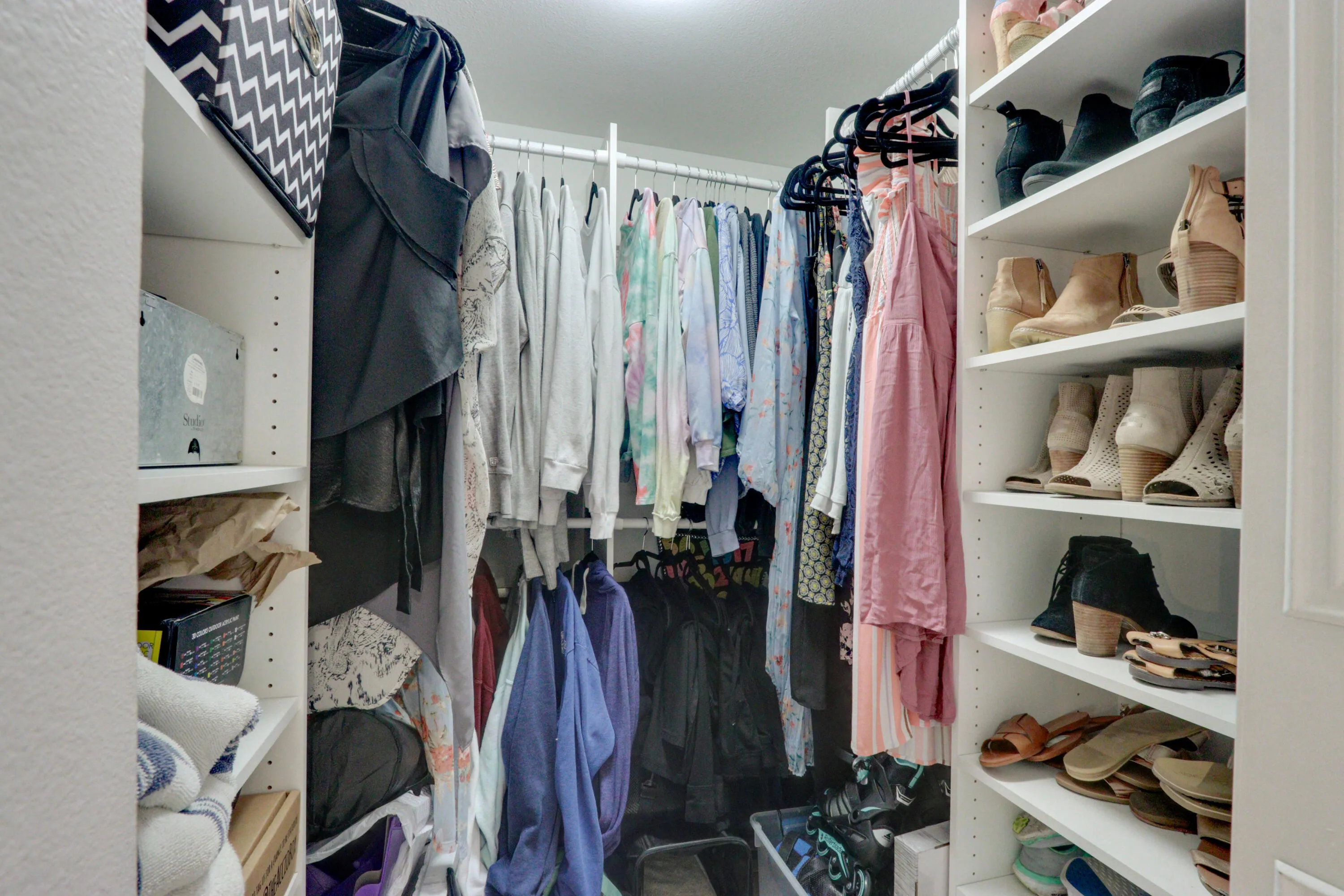 Custom closet system with white shelving, integrated hanging rods, and recessed lighting
