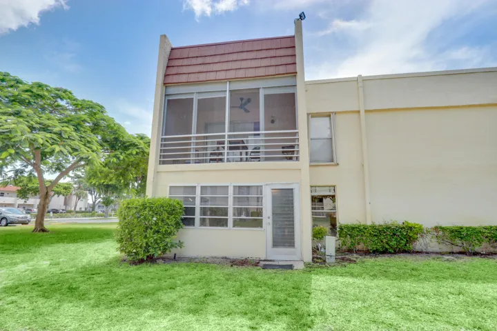 Rear exterior view of the condominium building surrounded by green space and mature landscaping