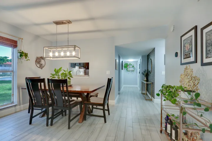 Recessed lighting, wood-finish flooring, and a contemporary chandelier illuminate this dining area