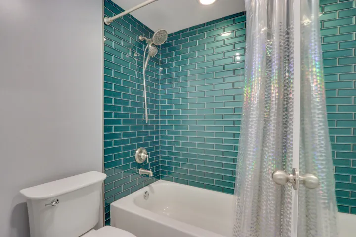 Bathtub with teal subway tile surround and brushed nickel fixtures