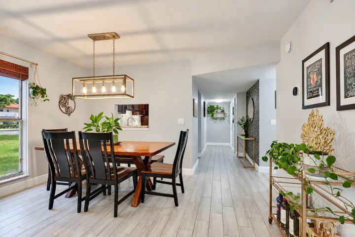 Recessed lighting, wood-finish flooring, and a contemporary chandelier illuminate this dining area
