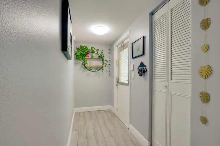 Wood-finish flooring, white louvered bifold doors, and a partial light gray wall finish