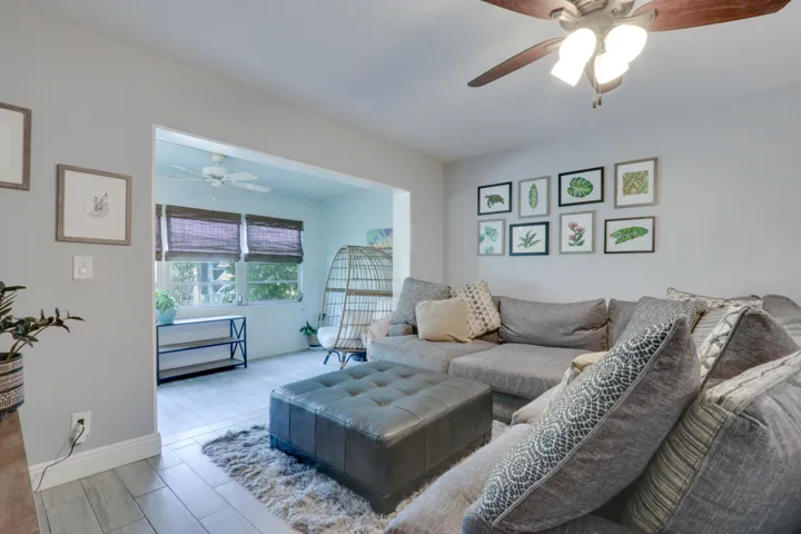 Light gray wall paint, wood-finish ceiling fan with integrated lighting, and light-toned tile flooring