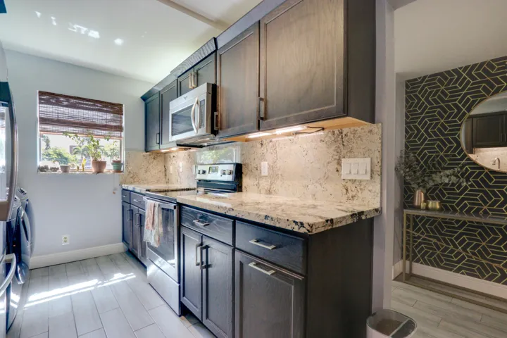 Kitchen featuring dark wood-finish cabinetry, light-toned countertops, tile flooring, and stainless steel appliances