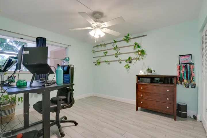 Light-toned wood-finish flooring, white ceiling fan, and window with natural light