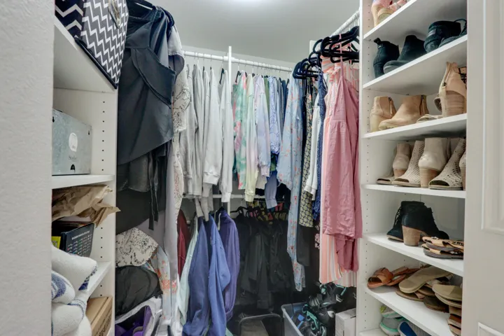 Custom closet system with white shelving, integrated hanging rods, and recessed lighting
