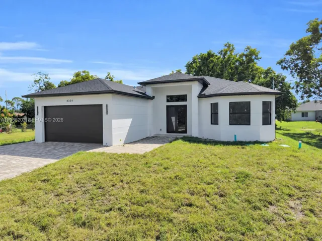 Single-story exterior featuring white stucco finish, dark-toned shingle roof, two-car garage, glass-panel front door, and paved driveway