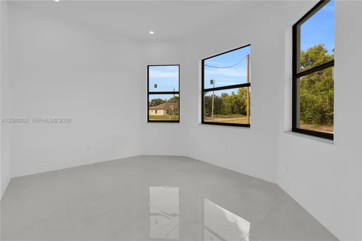 Interior space featuring large-format light-toned tile flooring, recessed lighting, and expansive windows with dark frames
