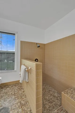 Walk-in shower with tiled walls, integrated bench, and mosaic tile flooring