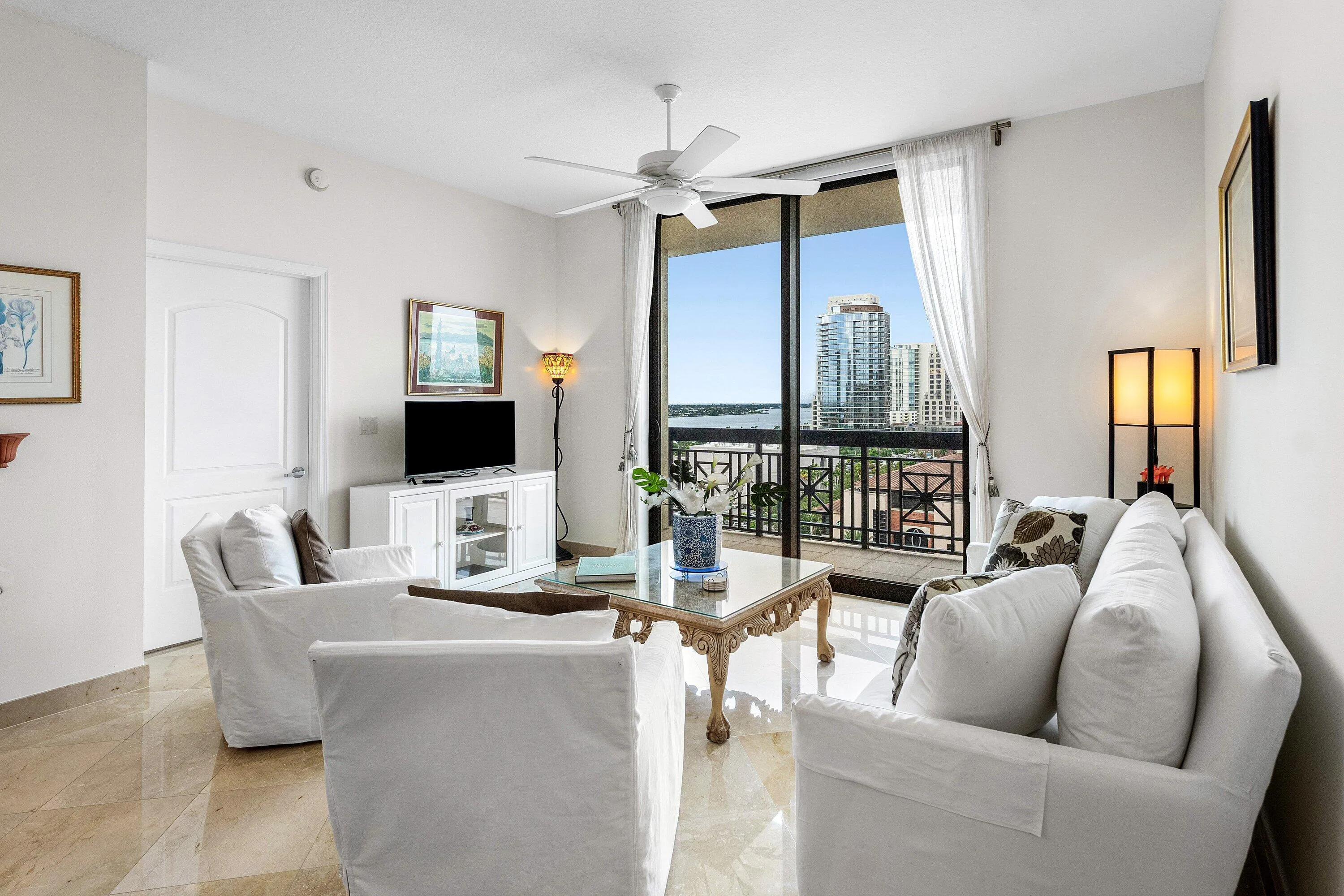 Expansive glass sliding doors open to a balcony with metal railings, offering city and Intracoastal views