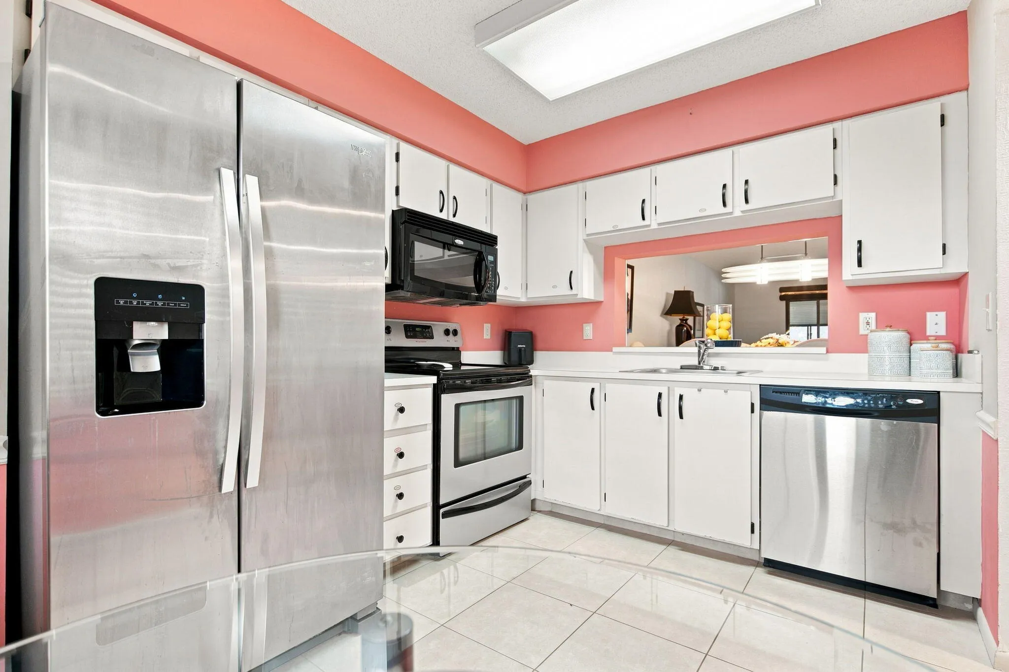 Stainless steel side-by-side refrigerator, stainless steel dishwasher, and white cabinetry with black hardware