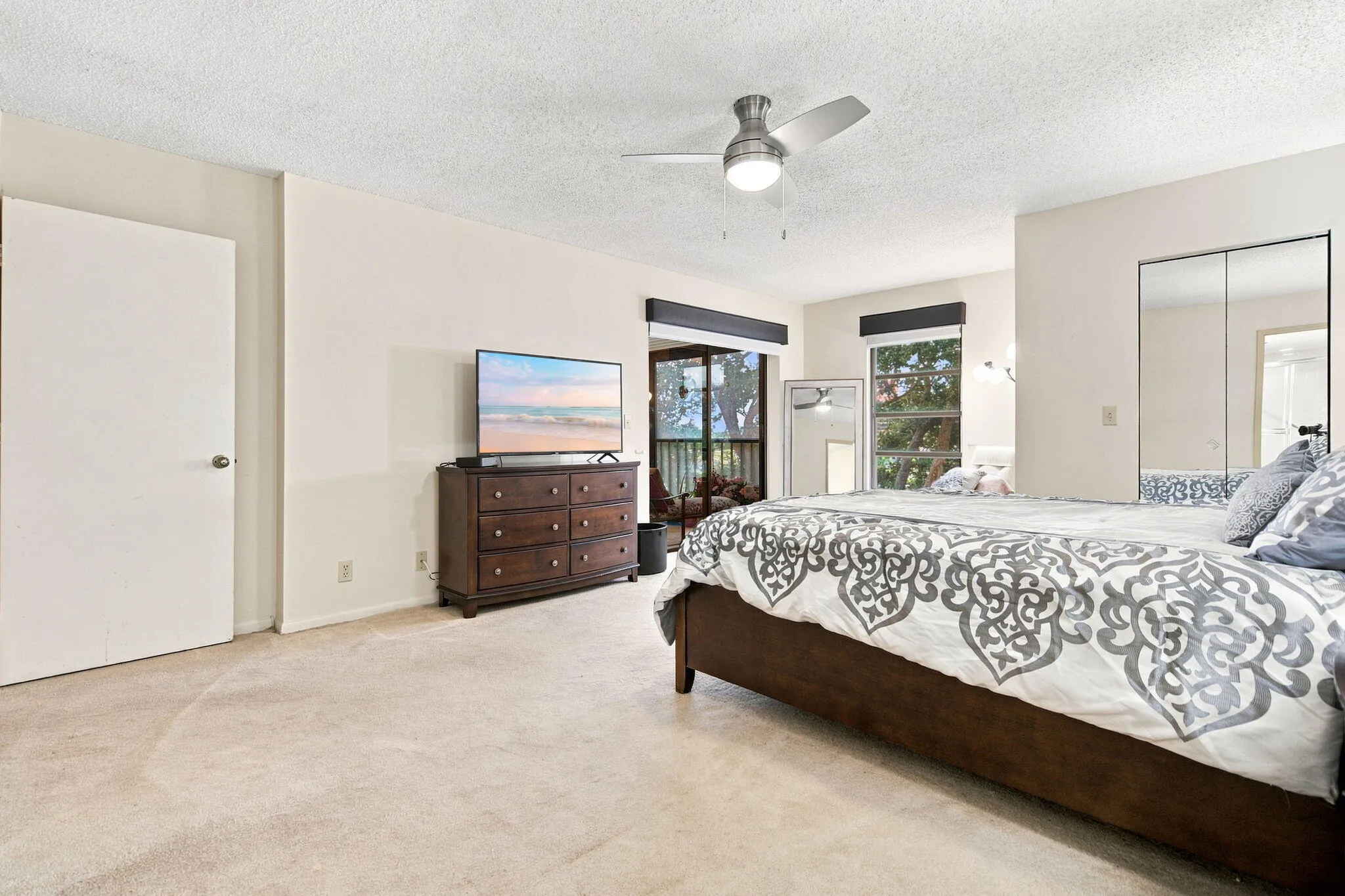Recessed balcony with opaque glass paneling, expansive glass sliding doors, and carpeted flooring