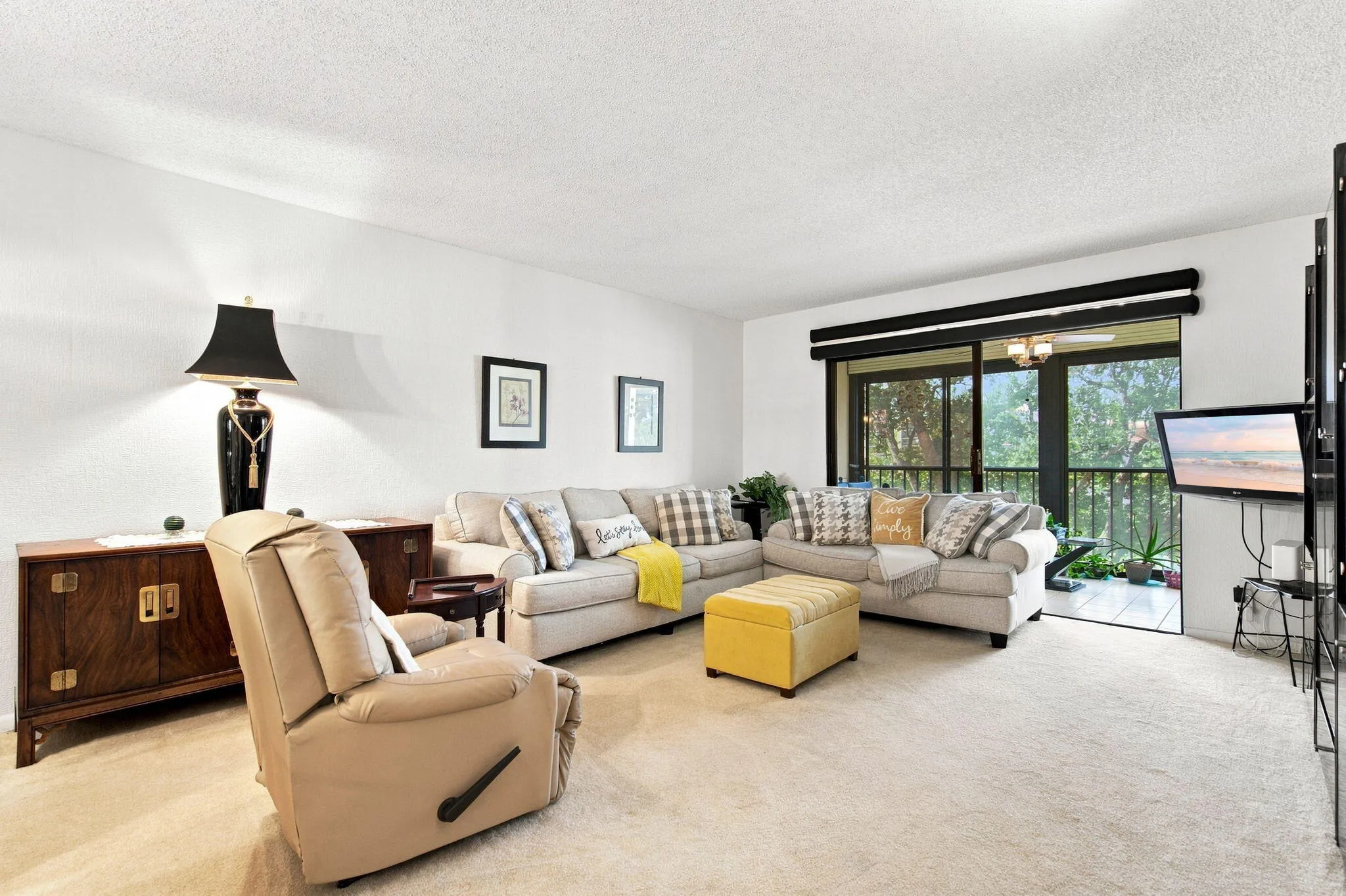 Carpeted living area with white walls and a built-in ceiling fan