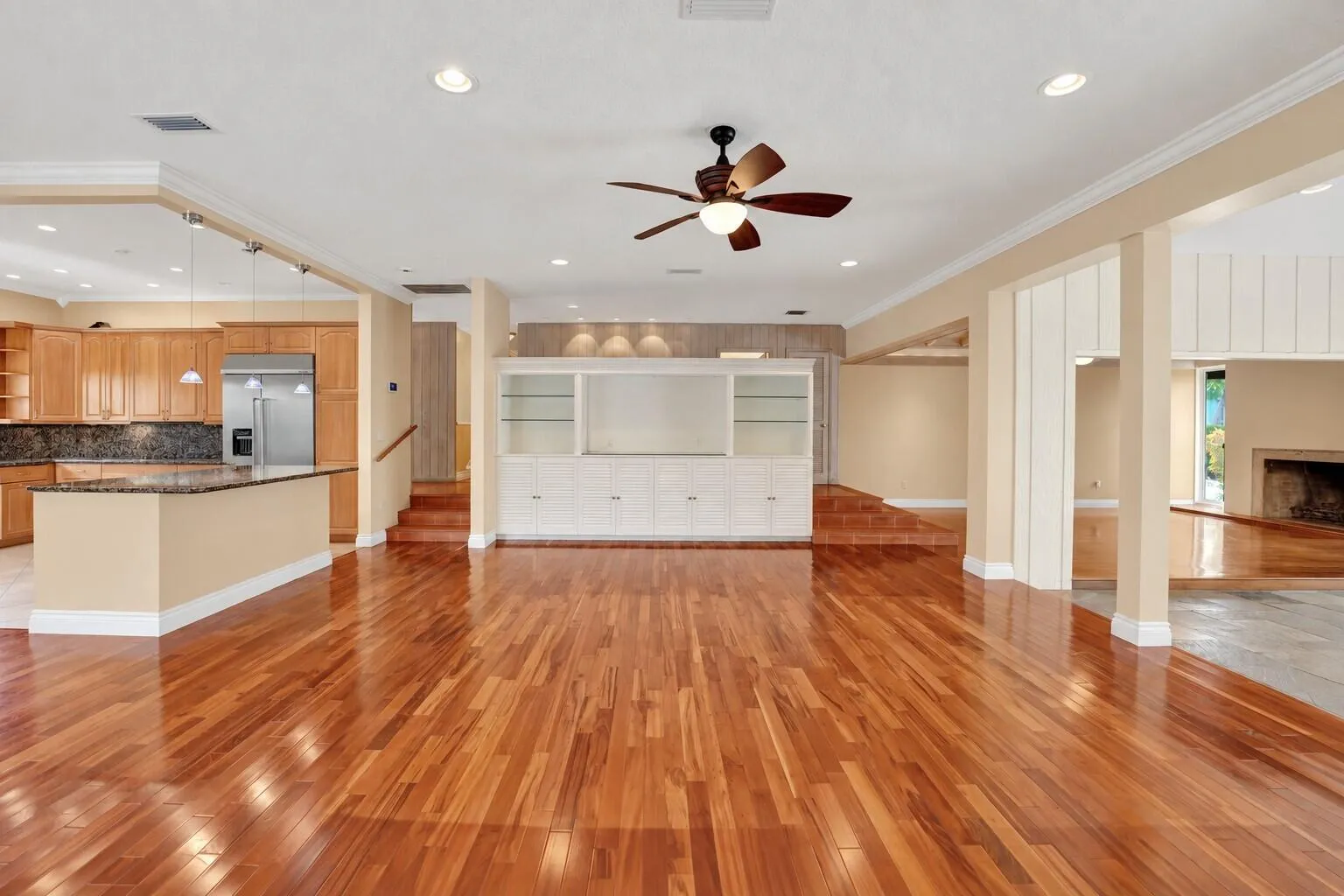 Hardwood flooring, recessed lighting, built-in cabinetry, kitchen island with dark countertop, stainless steel refrigerator