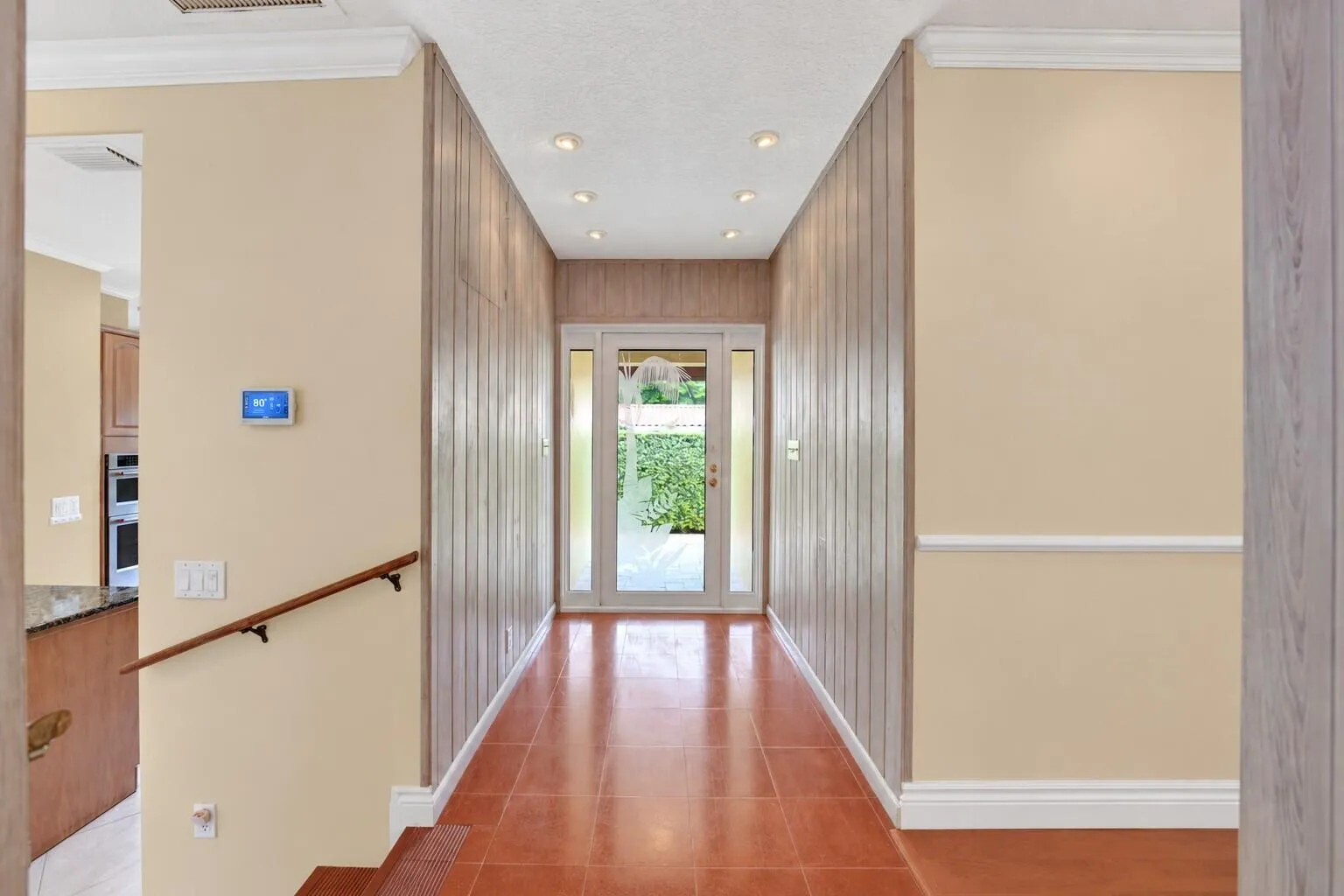 Entryway featuring tile flooring, recessed lighting, wood paneling, and a transom window door with sidelights