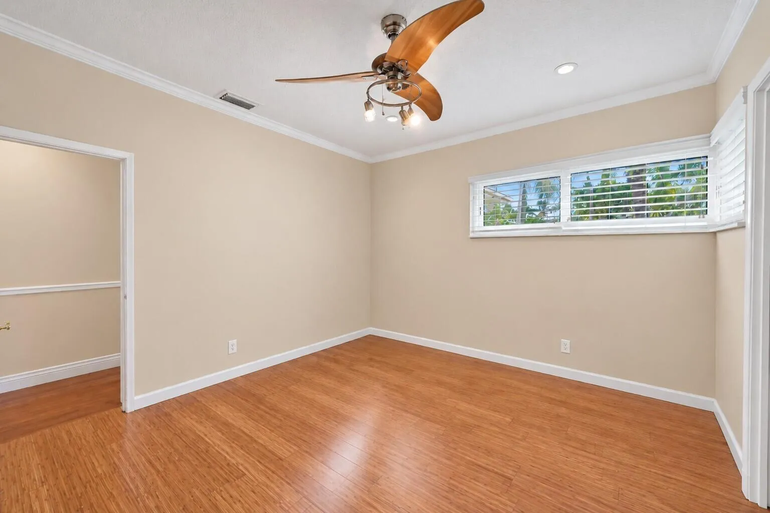 Wood-finish flooring, crown molding, a ceiling fan with integrated lighting, recessed lighting, and horizontal windows with plantation shutters