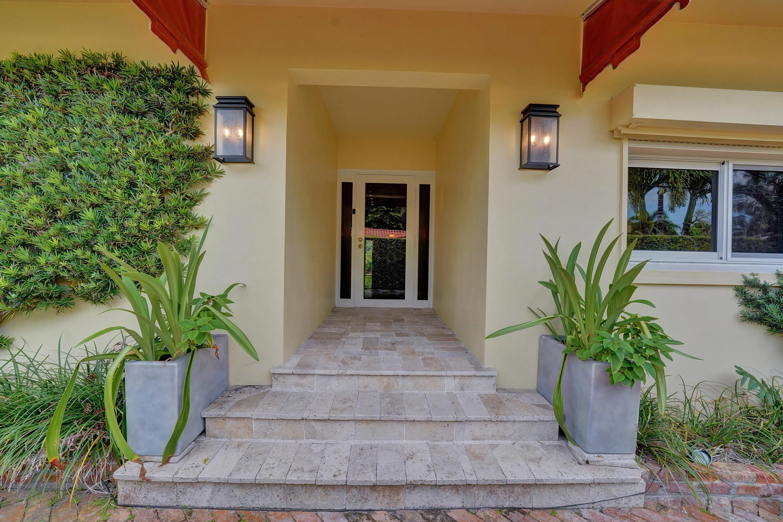 Recessed entry featuring a glass paneled door, stone steps, and wall-mounted exterior light fixtures