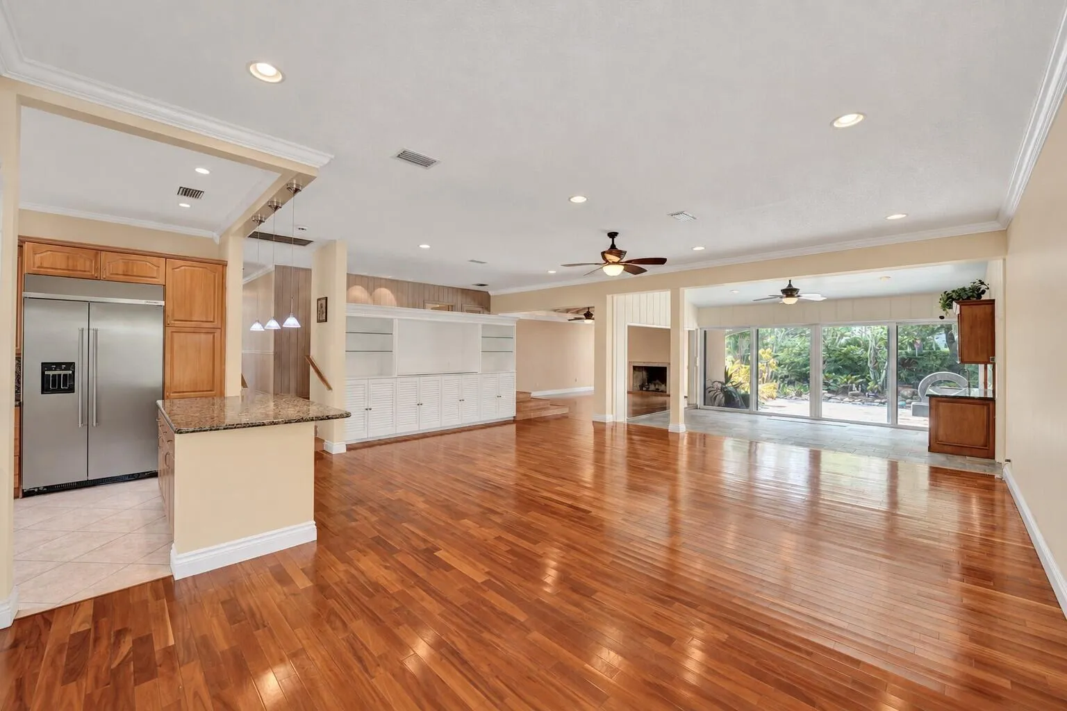 Expansive room with wood-finish flooring, recessed lighting, and crown molding. All wall color has been virtually enhanced.
