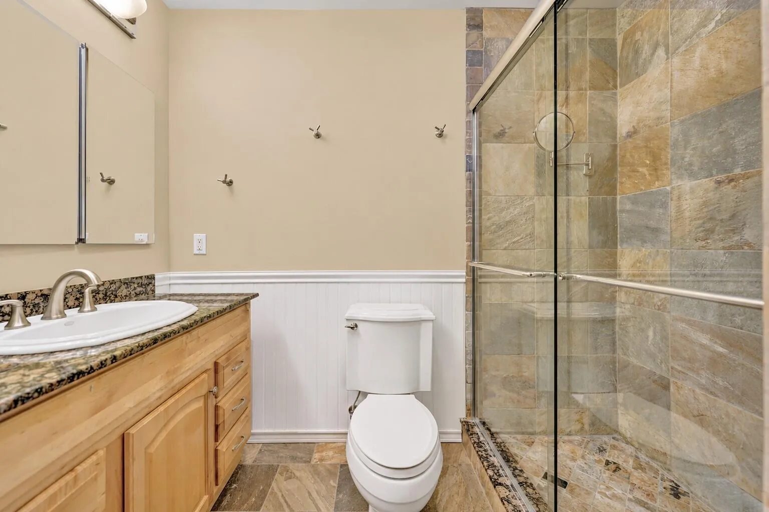 Single vanity with a granite countertop, undermount sink, and wood-finish cabinetry