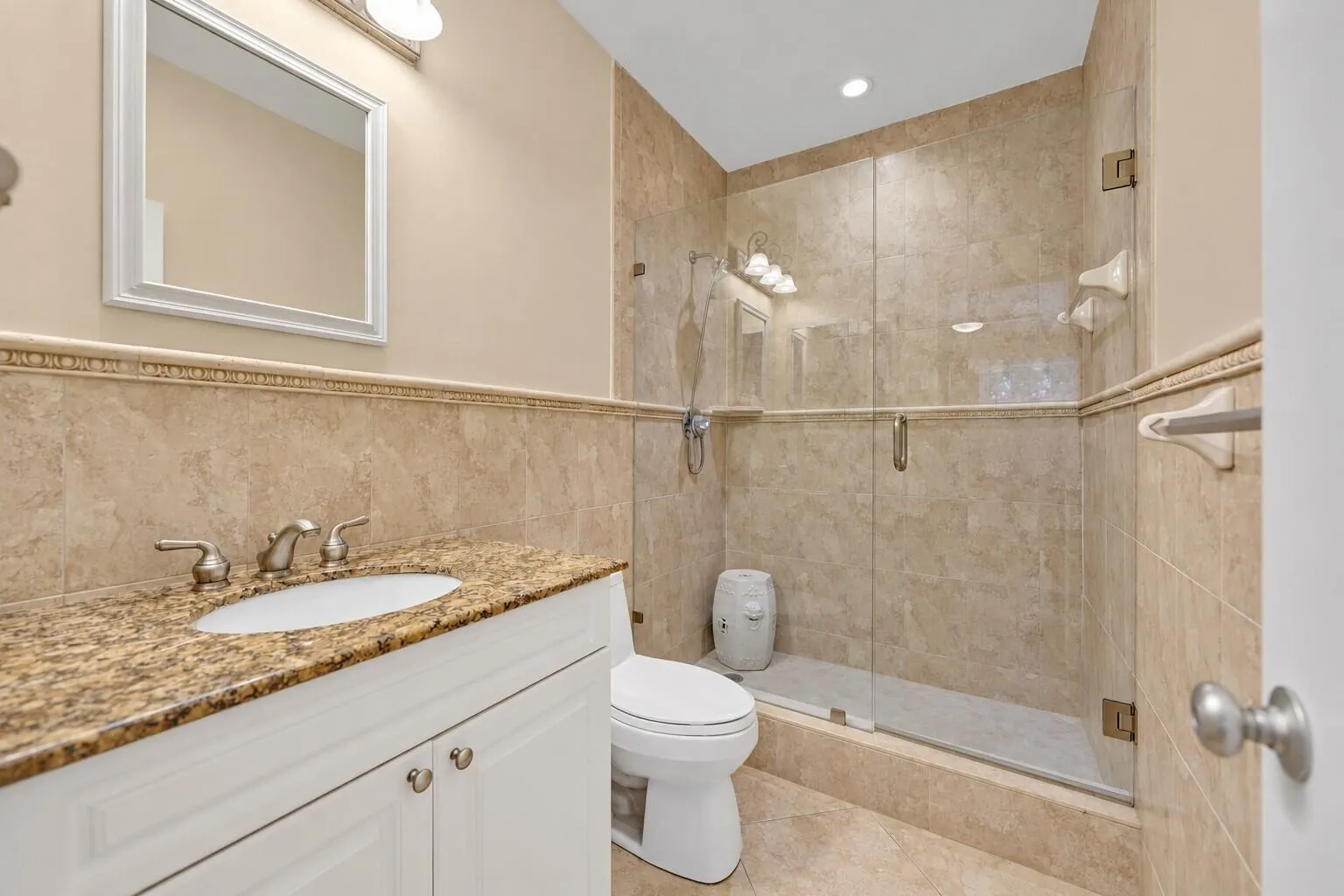 Vanity with an integrated sink, granite countertop, and white cabinetry