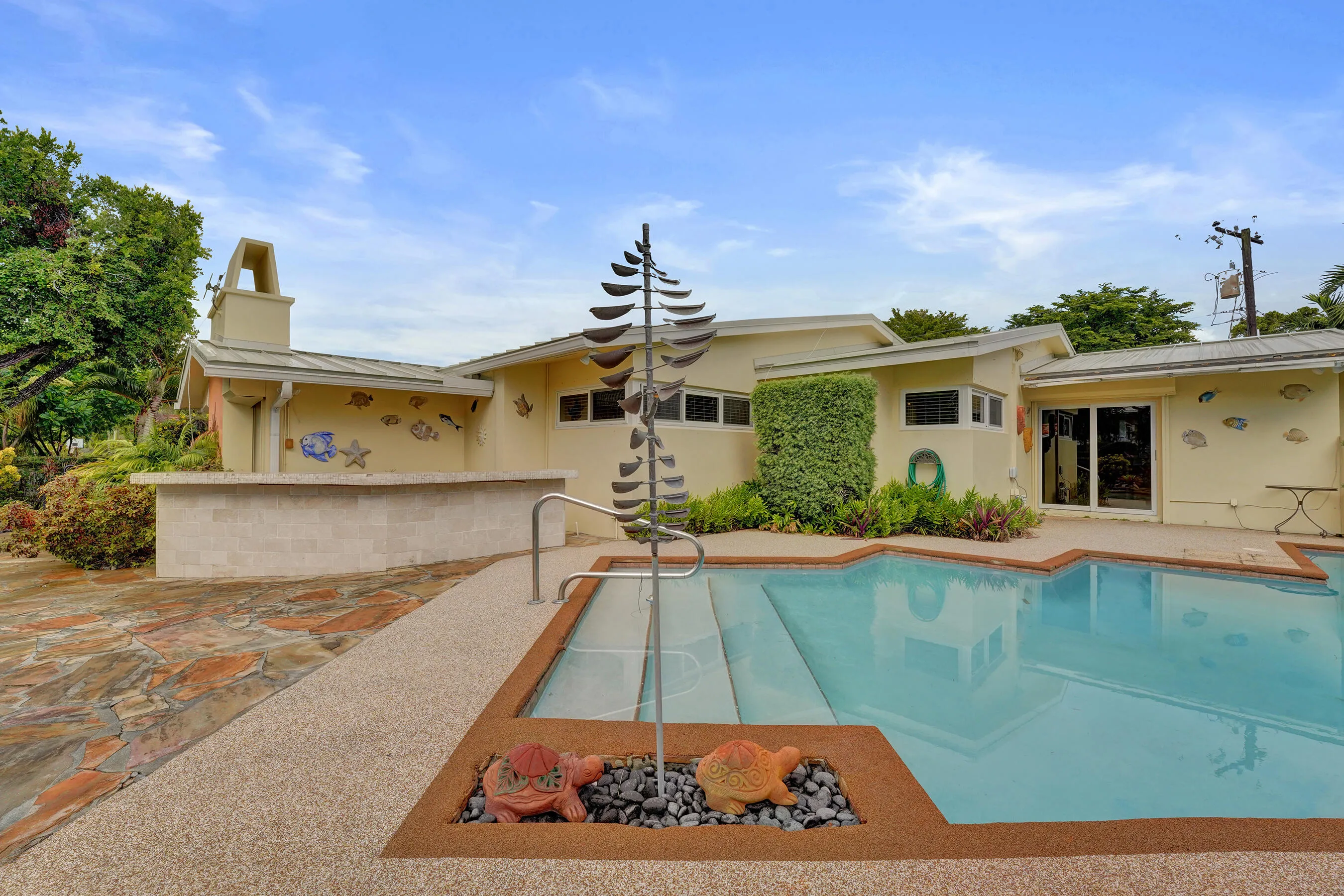 Swimming pool with integrated steps, surrounded by exposed aggregate decking and natural stone paving