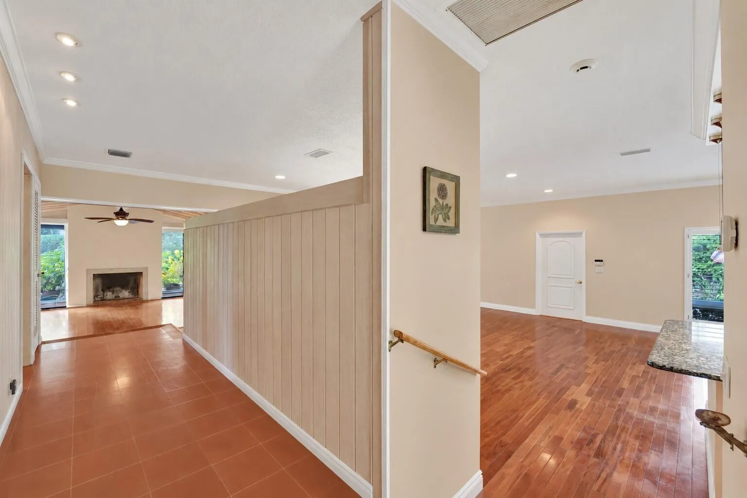 Recessed lighting, wood-finish flooring, terra cotta tile, built-in fireplace, and a light wood handrail. Wall color has been virtually altered.