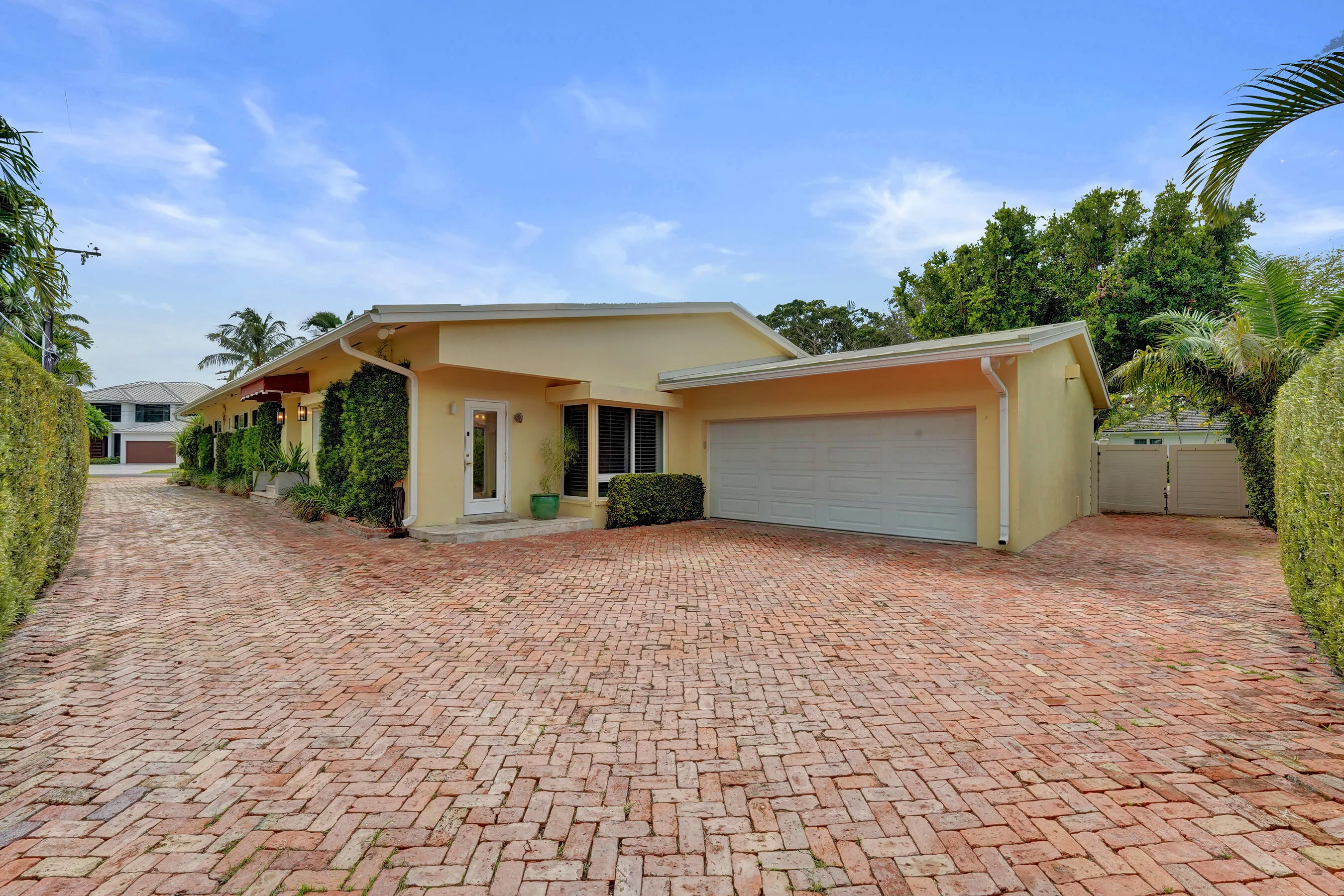 Driveway features plenty of space, leads to two-car garage, brick paver driveway, and mature landscaping.