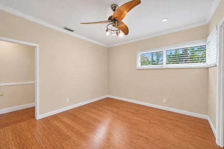 Wood-finish flooring, crown molding, a ceiling fan with integrated lighting, recessed lighting, and horizontal windows with plantation shutters