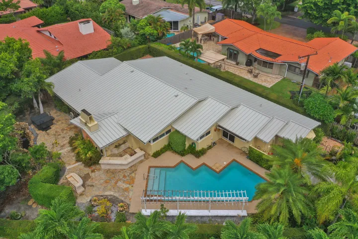 Expansive residence featuring a multi-gabled roofline, a geometric-shaped swimming pool, and extensive stone hardscaping