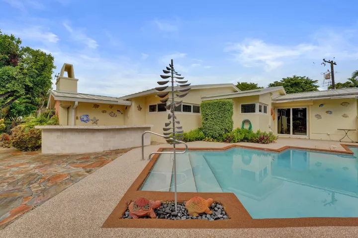 Swimming pool with integrated steps, surrounded by exposed aggregate decking and natural stone paving