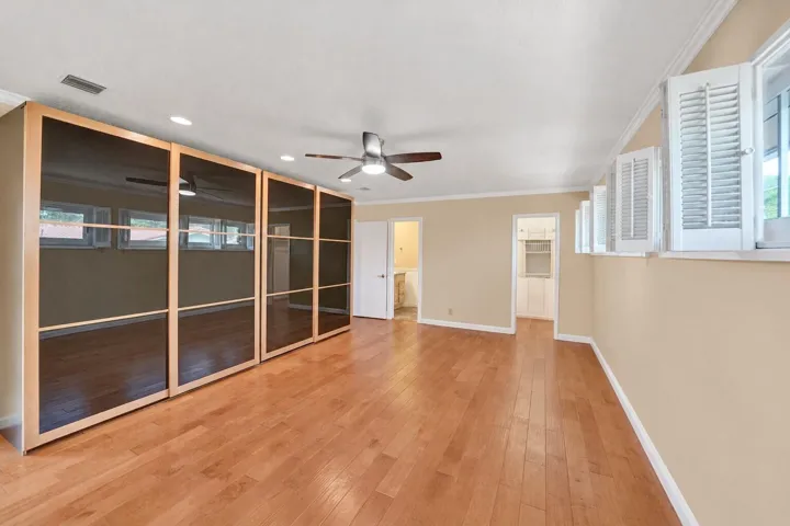 Hardwood flooring, recessed lighting, ceiling fan, crown molding, and built-in cabinetry with glass panel doors
