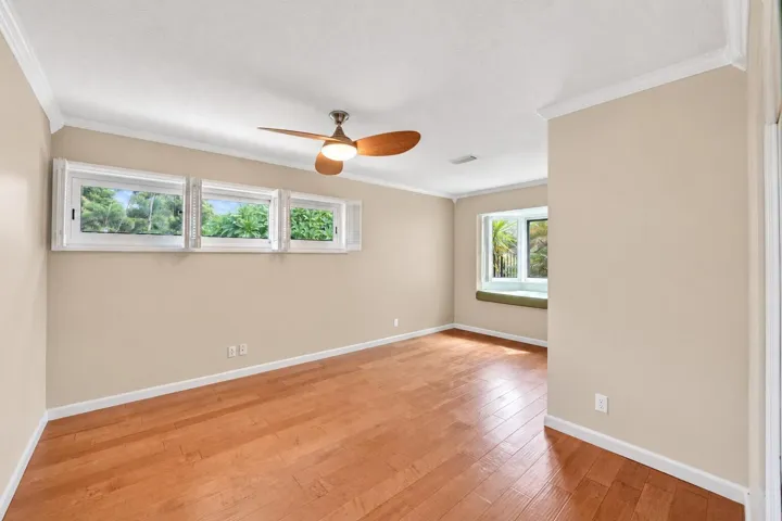 Hardwood-finish flooring, crown molding, and a ceiling fan with integrated lighting