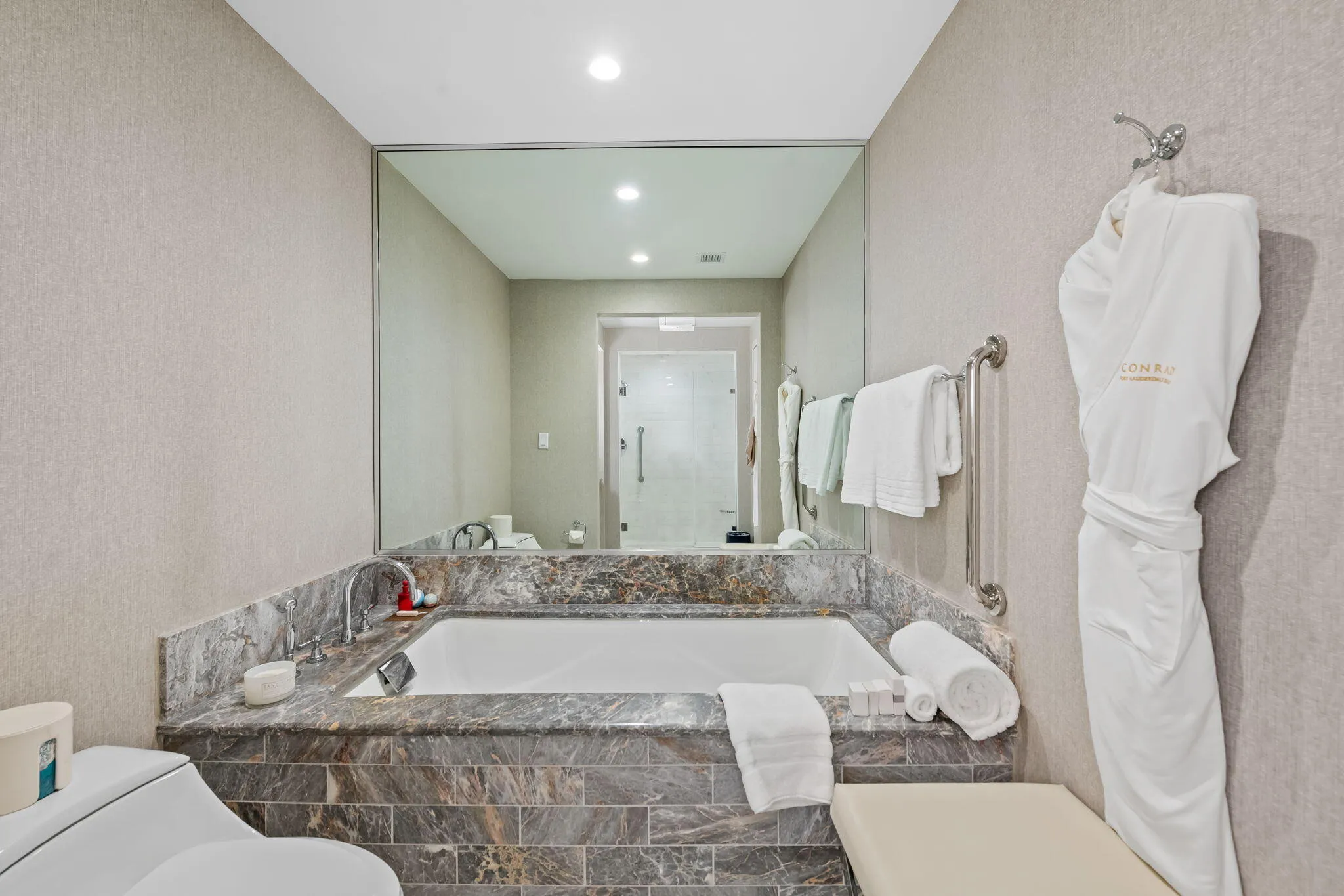 Built-in soaking tub with a stone surround and integrated faucet, complemented by a large wall-mounted mirror