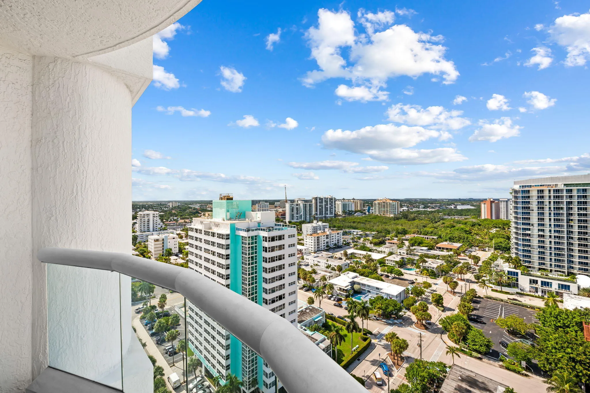 Expansive balcony with glass panel railing and painted stucco exterior