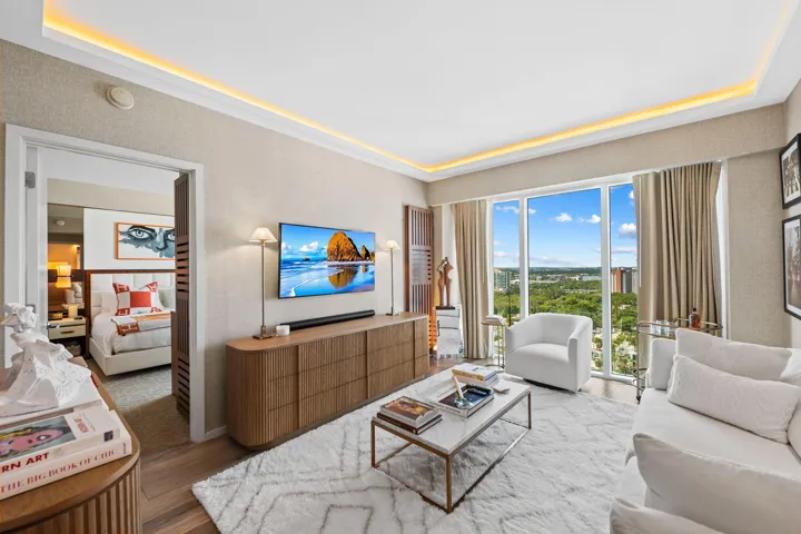 Recessed ceiling lighting, full-height windows, wood-finish flooring, and a built-in media console