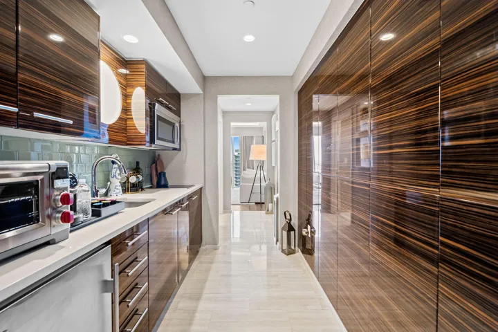 Integrated kitchen cabinetry with wood-grain finish and stainless steel hardware