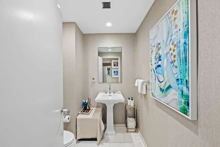 Pedestal sink with polished chrome fixtures, recessed lighting, wall-mounted mirror, and textural wall covering
