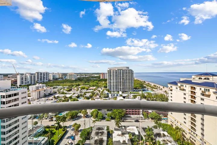 Expansive ocean and cityscape backdrop from a balcony with a glass and metal railing system