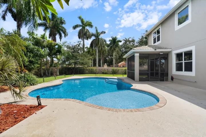 Resort-style pool with integrated steps, surrounded by concrete decking and mature tropical landscaping