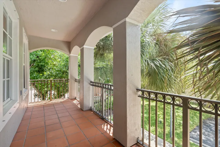 Expansive covered balcony featuring terra cotta tile flooring, arched openings, and decorative metal railings