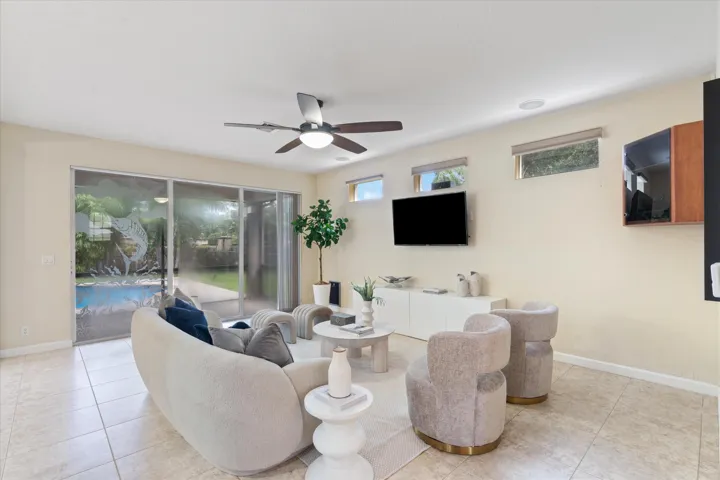 Sliding glass doors featuring etched glass detail, ceramic tile flooring, ceiling fan with integrated lighting, and high-mounted windows