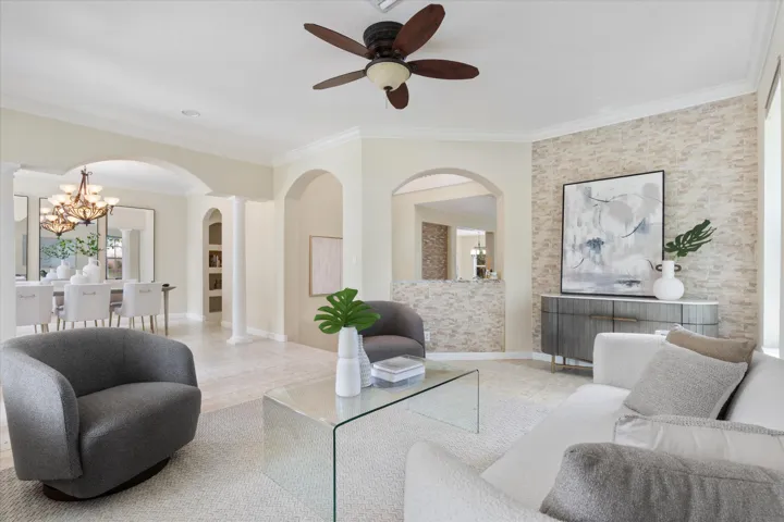Arched doorways, crown molding, stone accent wall, recessed lighting, and a ceiling fan with integrated lighting
