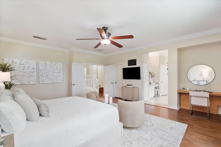 Hardwood flooring, crown molding, double doors, and a ceiling fan with integrated lighting