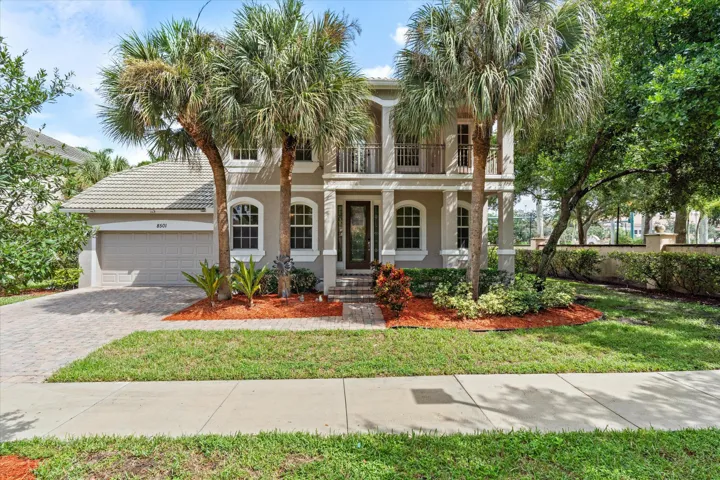 Two-story residence featuring a tile roof, an integrated two-car garage, and a paver driveway