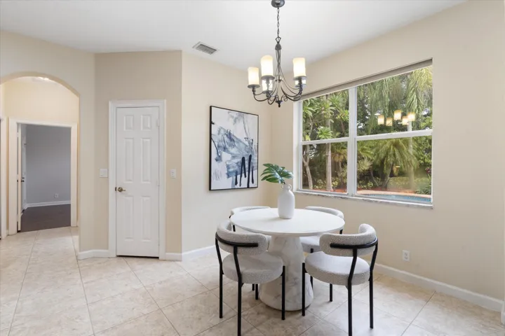 Tiled flooring, arched hallway entry, paneled interior doors, large window, and ceiling-mounted chandelier
