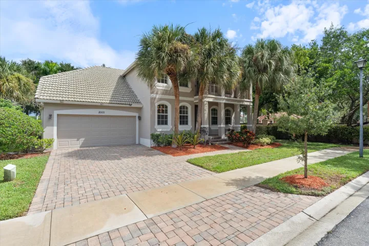Stucco exterior with a tiled roof, two-car garage, and a paver driveway