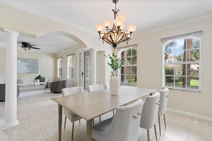 Tiled flooring throughout, arched doorways, decorative columns, and a multi-light chandelier